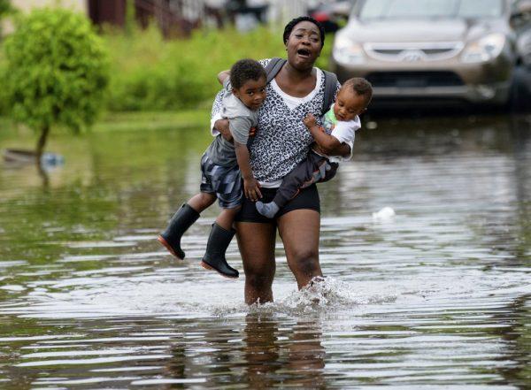 Terrian Jones reacts as she feels something moving in the water at her feet as she carries Drew and Chance Furlough to their mother on Belfast Street in New Orleans during flooding from a storm in the Gulf Mexico that dumped lots of rain on July 10, 2019. (Matthew Hinton/AP Photo)