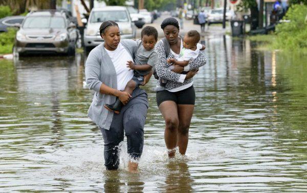 Jalana Furlough carries her son Drew Furlough as Terrian Jones carries Chance Furlough in New Orleans after flooding on July 10, 2019. (Matthew Hinton/AP Photo)