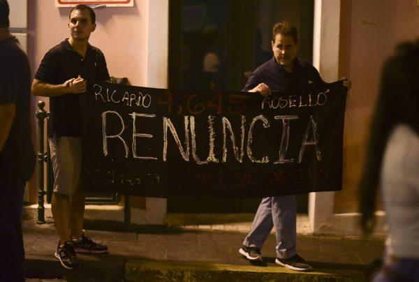 Citizens carrying a banner that reads in Spanish "Ricardo Rosello, renounce" protest near the executive mansion denouncing a wave of arrests for corruption that has shaken the country and demanding the resignation of Gov. Ricardo Rosello, in San Juan, Puerto Rico on July 11, 2019. (Carlos Giusti/AP)