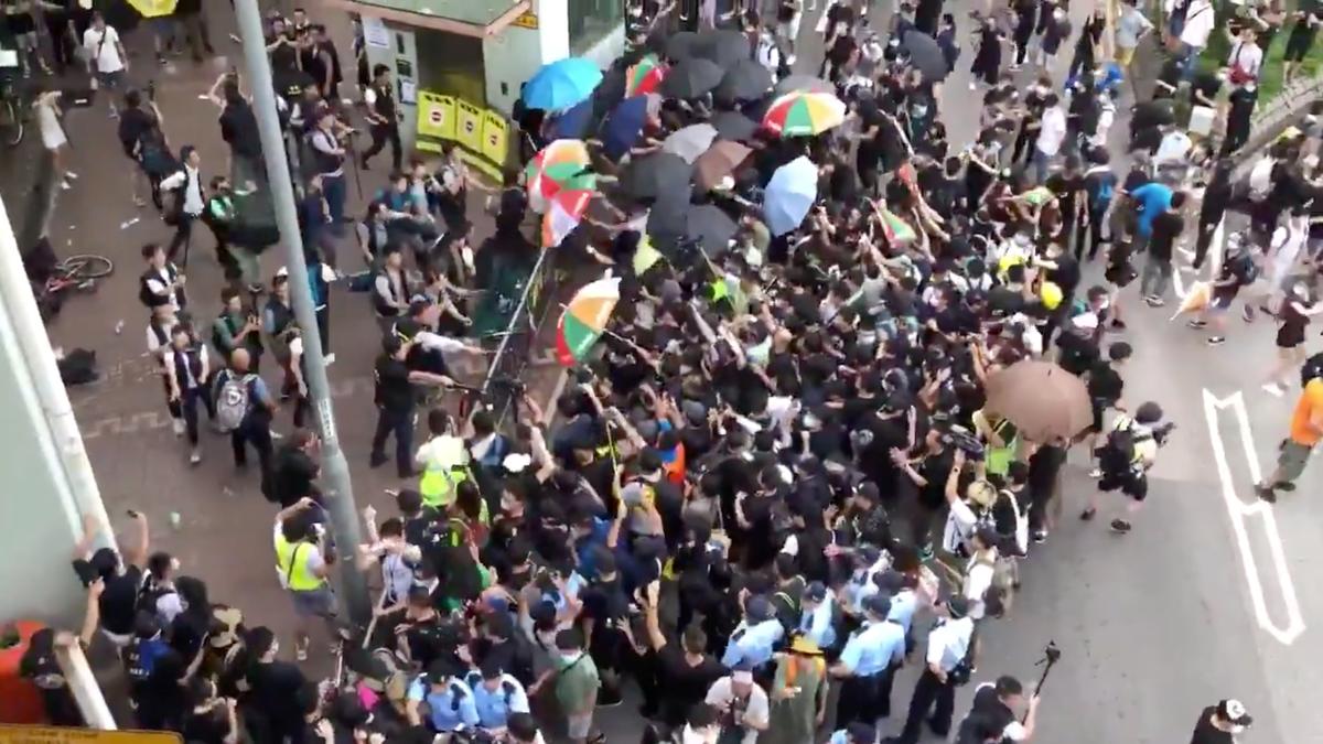 Demonstrators hold their umbrellas out across a barricade at plainclothes police with batons in Sheung Shui, Hong Kong, China on July 13, 2019 in this still image taken from social media video. (Aaron Mc Nicholas via Reuters)