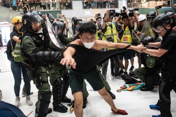 Police officers tear the shirt of a protester during a clash inside a shopping arcade after a rally against a controversial extradition law proposal in Sha Tin district of Hong Kong on July 14, 2019. (PHILIP FONG/AFP/Getty Images)