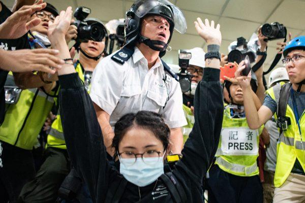A protester gestures as a policeman looks on inside a shopping arcade in after a rally against a controversial extradition law proposal in Sha Tin district of Hong Kong on July 14, 2019. (PHILIP FONG/AFP/Getty Images)
