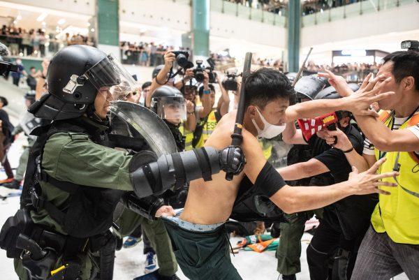 Police officers tear the shirt off a protester during a clash inside a shopping arcade after a rally against a controversial extradition bill in Sha Tin district of Hong Kong on July 14, 2019. (Philip Fong/AFP/Getty Images)