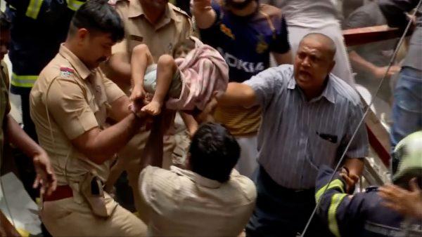 Officials rescue a child after a building collapsed in Mumbai, India on July 16, 2019. (Still Image from video via Reuters)