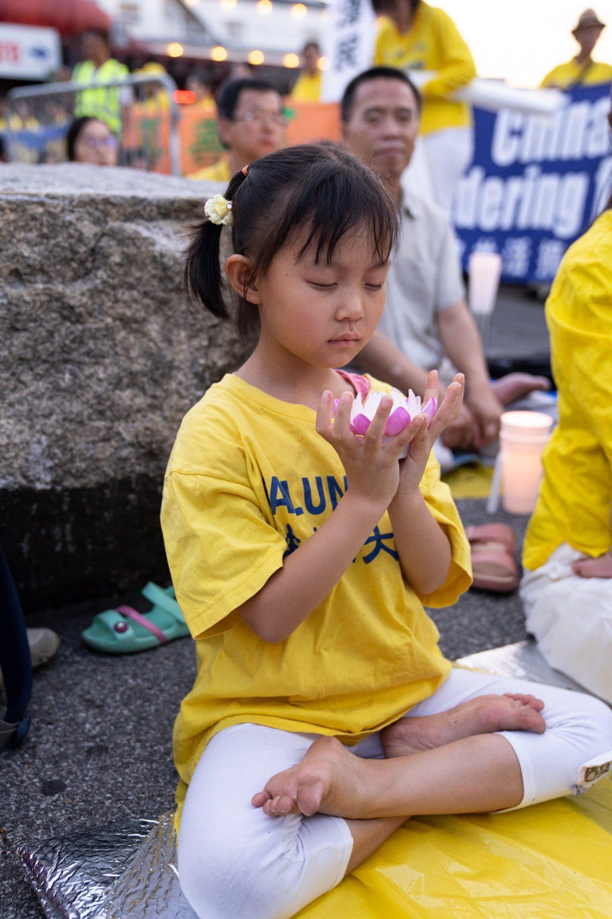 A girl sits at the vigil commemorating the 20th anniversary of the persecution of Falun Gong in New York, N.Y., on July 15, 2019. (Larry Dye/The Epoch Times)
