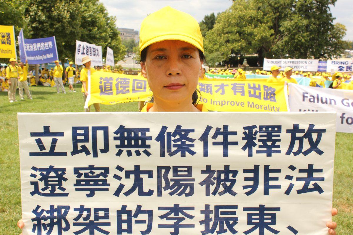 Falun Gong practitioner Li Shuyin holds a sign calling for the release of imprisoned Falun Gong practitioners from her hometown of Shenyang, Liaoning, in Washington, on July 18, 2019. (Eva Fu/The Epoch Times)