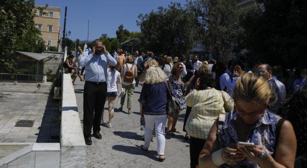 People speak on their phones as they stand outside the building they work in, after a strong earthquake hit near the Greek capital of Athens, on July 19, 2019. (Petros Giannakouris/AP Photo)