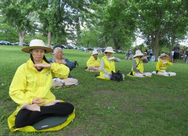Falun Gong adherents meditating at Mooney’s Bay Park in Ottawa during the Dragon Boat Festival, but not on the festival grounds, on June 22, 2019. (The Epoch Times)