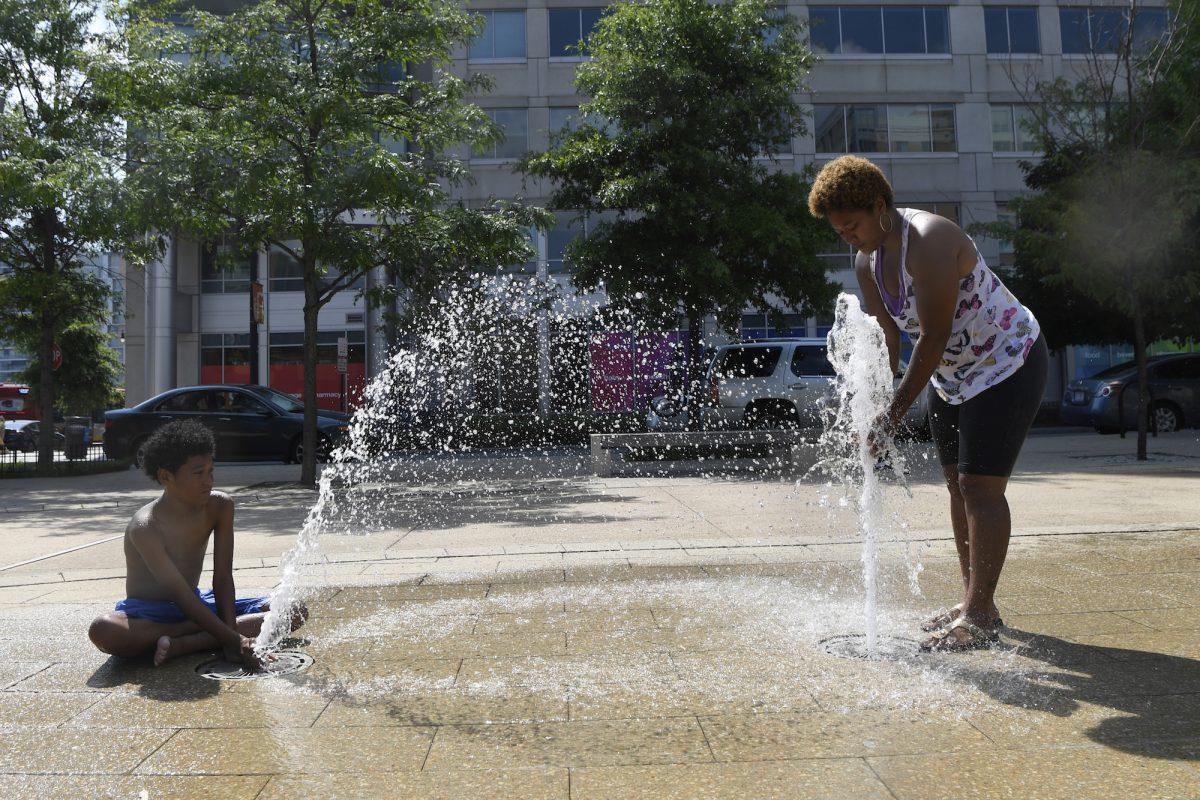 Karen Frazier of Capitol Heights, Md., right, and her son Amari Rogers, 11, left, play in a fountain in Washington, on July 20, 2019. (Susan Walsh/AP Photo)