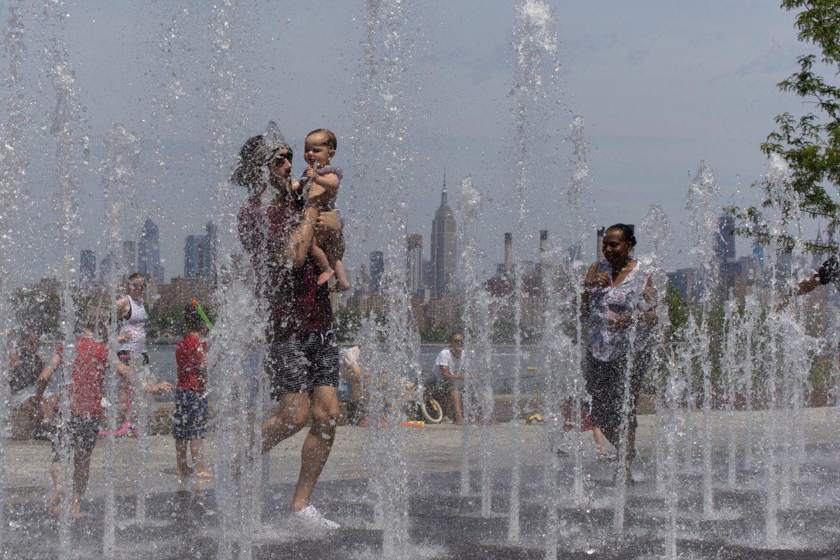 People enjoy the day playing with water as the Empire State Building is seen from Williamsburg in Brooklyn, N.Y., on July 20, 2019. (Eduardo Munoz Alvarez/AP Photo)