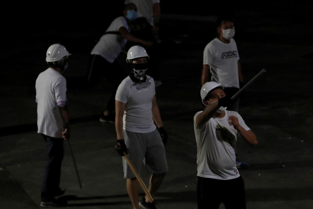 Men in white T-shirts and carrying poles react in Yuen Long after attacking anti-extradition bill demonstrators at a train station in Hong Kong, China on July 22, 2019. (Tyrone Siu/Reuters)