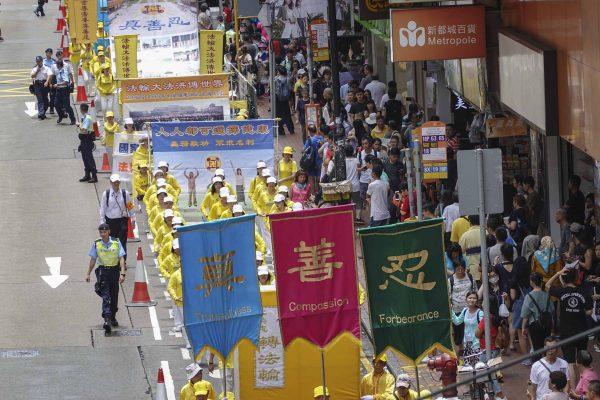 Practitioners of Falun Gong march to voice opposition to the persecution of Falun Gong in China, in Hong Kong on July 21, 2019. The three banners in the front show the Chinese characters of "Truthfulness," "Compassion," and "Forbearance," the three principles of the spiritual practice. (Yu Kong/The Epoch Times)