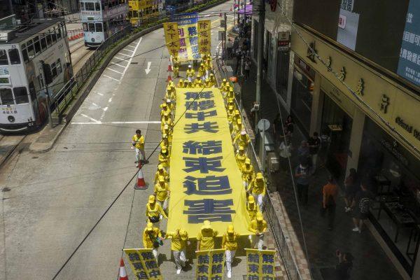 Practitioners of Falun Gong, a spiritual practice, march to voice opposition to the persecution of Falun Gong in China, in Hong Kong on July 21, 2019. The long banner calls for an end to the persecution of Falun Gong launched in 1999 by the Chinese Communist Party. (Yu Kong/The Epoch Times)