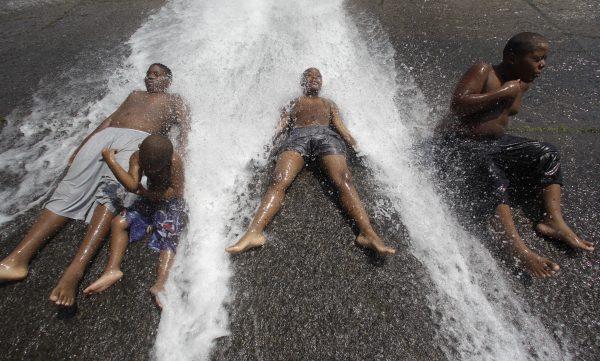 Kids play in an open fire hydrant during the heat wave in Detroit. (Paul Sancya/AP)