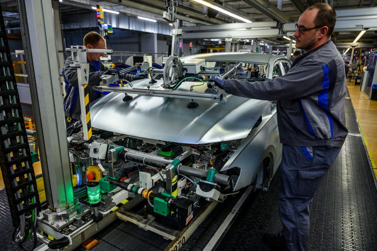 Workers fit a hood on a car on a production line at German car manufacturing giant Volkswagen's headquarters in Wolfsburg, Germany, on March 1, 2019. (John McDougall/AFP/Getty Images)