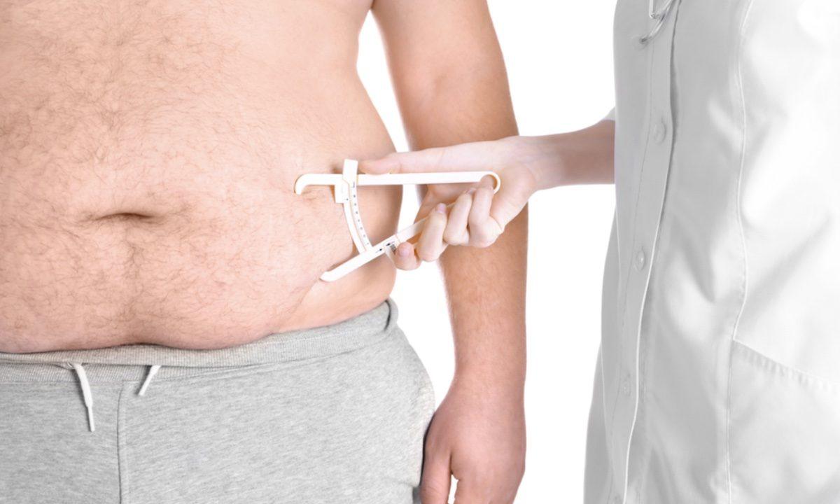 Stock image of a doctor measuring fat on a man's stomach. (Africa Studio/Shutterstock)
