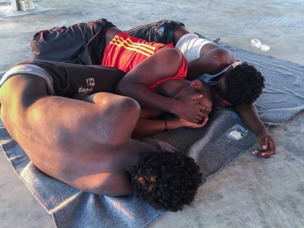 Rescued migrants rest on a coast some 60 miles east of Tripoli, Libya, on July 25, 2019. (Hazem Ahmed/AP Photo)