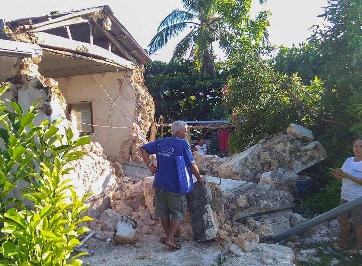 A resident looks at damaged houses in Itbayat town, Batanes islands, northern Philippines on Saturday July 27, 2019. Two strong earthquakes hours apart measuring 5.4 and 5.9 struck a group of sparsely populated islands in the Luzon Strait in the northern Philippines early Saturday, killing at least four people and injuring several others. (AP Photo/Agnes Salengua Nico)