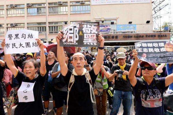 Protesters hold up signs saying how police had colluded with local gangs in a march on Yuen Long, Hong Kong, on July 27, 2019. (Song Bilong/The Epoch Times)