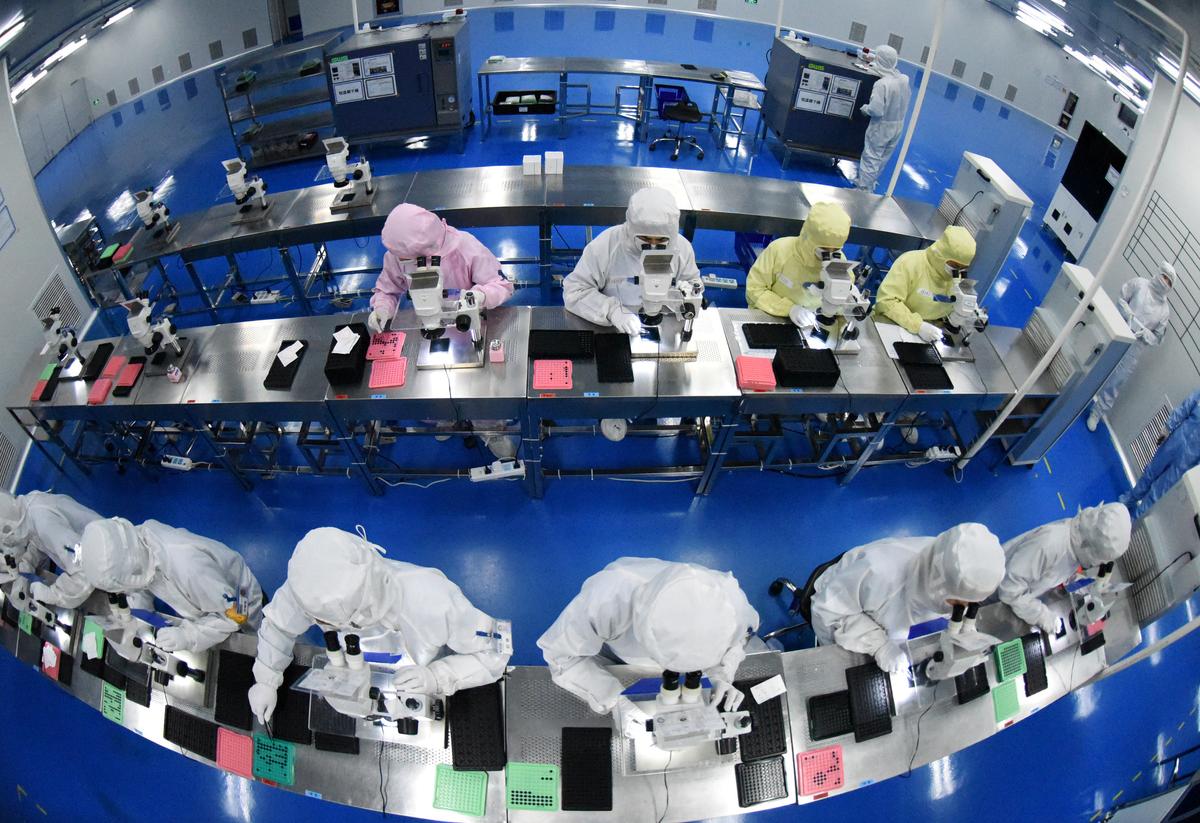 Employees work on a production line manufacturing camera lenses for cellphones at a factory in Lianyungang, Jiangsu Province, China on April 30, 2019. Picture taken with a fisheye lens. (China Daily via Reuters)