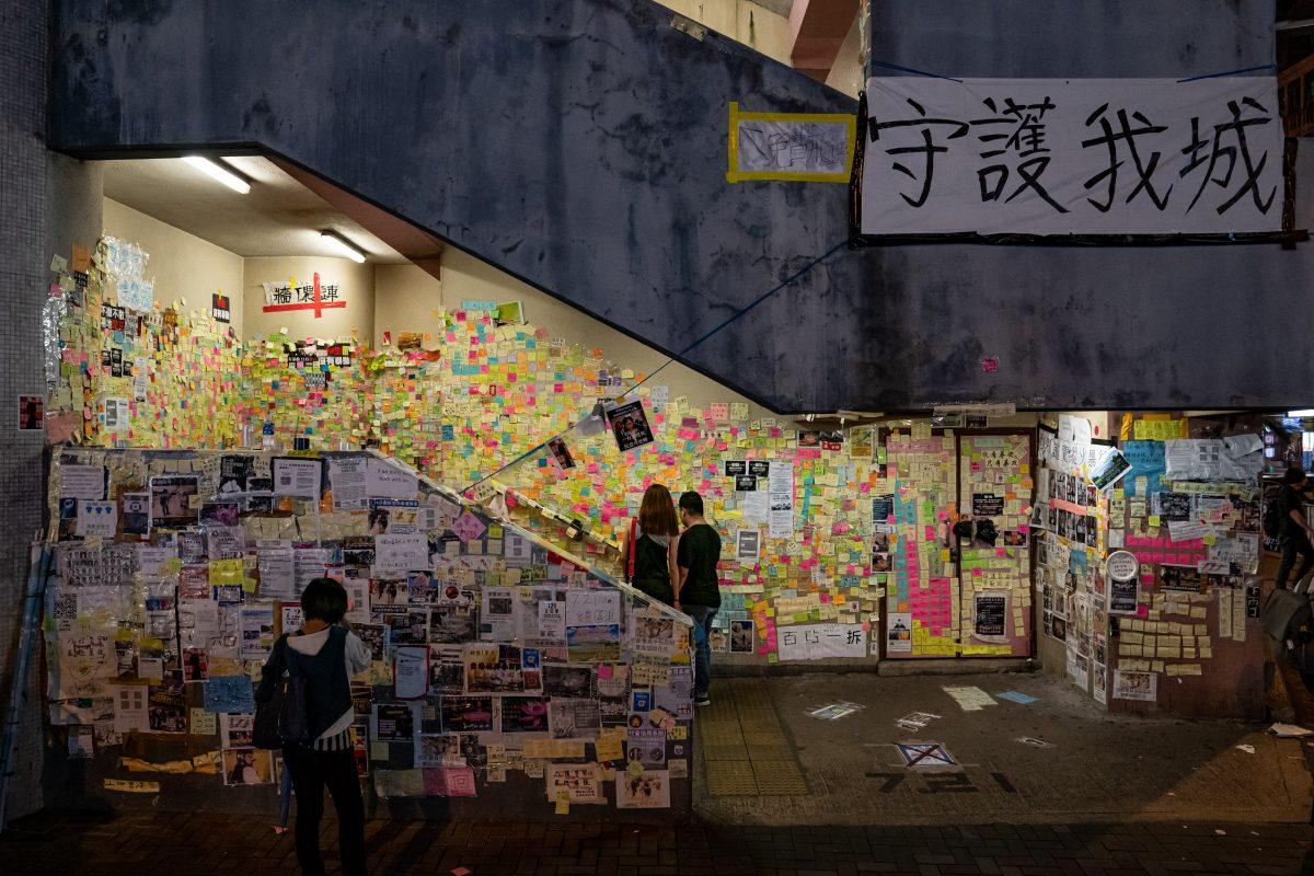 Pedestrians look at notes on a makeshift "Lennon Wall" at a flight of stairs in Sai Wan Ho district in Hong Kong, on July 20, 2019. The banner on the top right corner reads: "Safeguard My City." (Anthony Kwan/Getty Images)