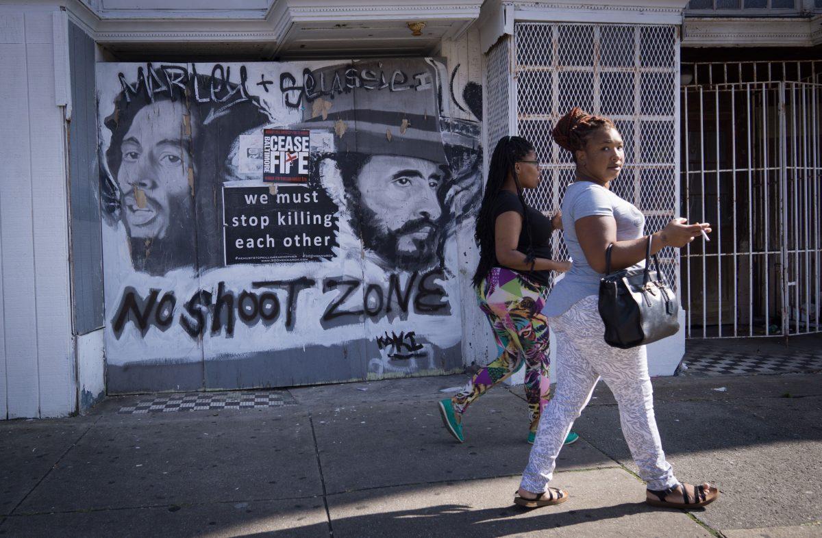 Women walk past a sign with a message to end gun violence in the Sandtown neighborhood of West Baltimore on Aug. 8, 2017. (MANDEL NGAN/AFP/Getty Images)