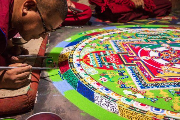 Tibetian monks constructing Mandala from color sand in Thiksay monastery. Mandalas transmit positive energies to the people who view them. (Shutterstock)