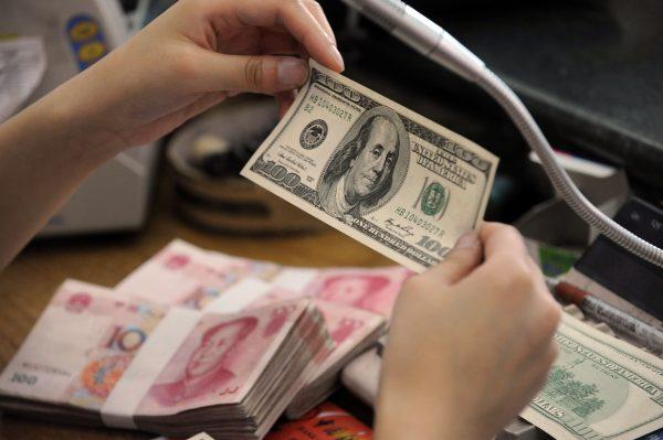 A Chinese bank worker checks a U.S. 100-dollar bill together with stacks of 100-yuan notes at a bank counter in Hefei City, Anhui Province, China, on Sept. 30, 2010. (STR/AFP/Getty Images)