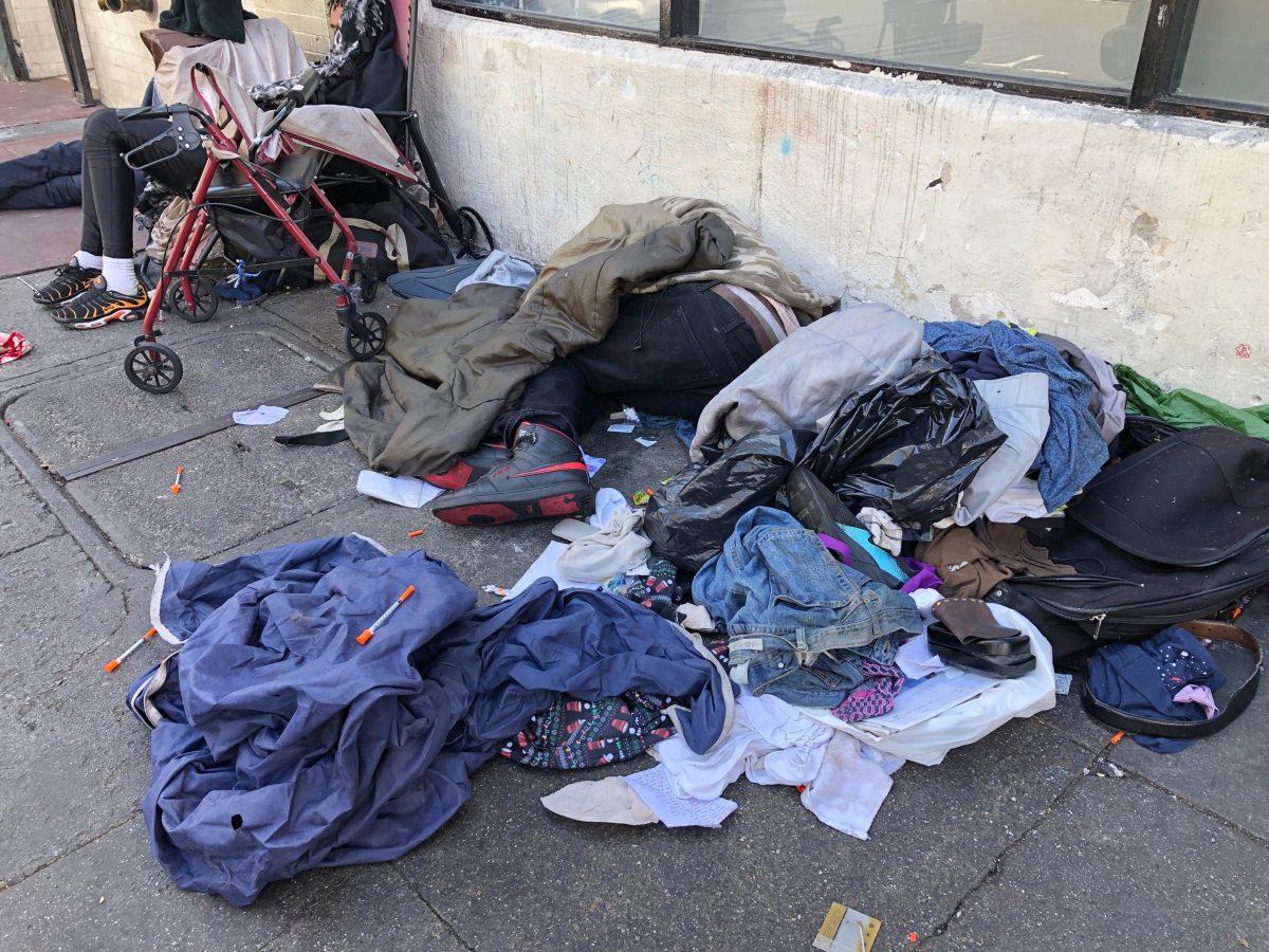 Sleeping people, discarded clothes and used needles sit across the street from a staffed "Pit Stop" public toilet in the Tenderloin neighborhood in San Francisco on July 25, 2019. (Janie Har/AP Photo)
