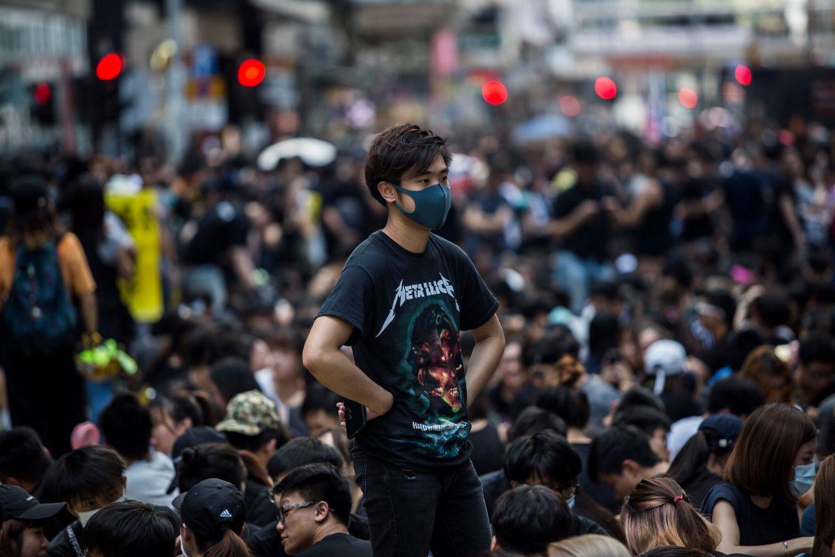 A masked protester stands among others gathering in Mong Kok during a general strike in Hong Kong on Aug. 5, 2019, as simultaneous rallies were held across seven districts. (Isaac Lawrence/AFP/Getty Images)