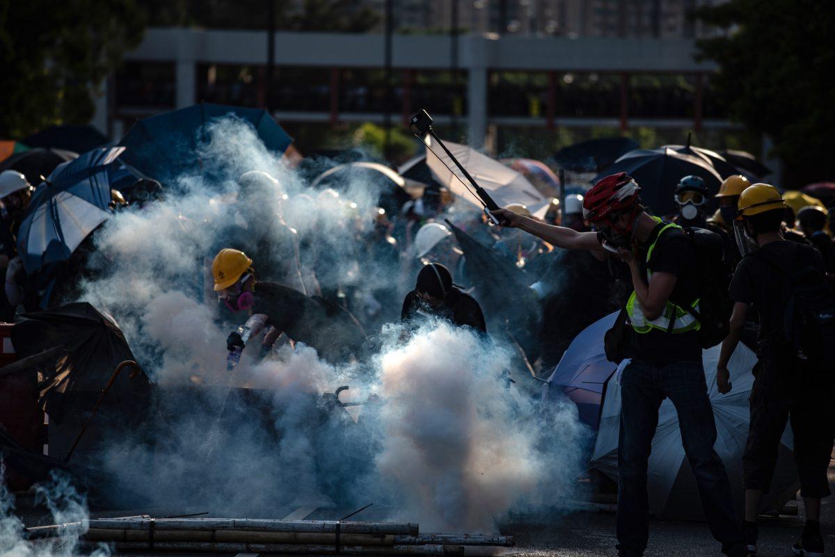 Protesters attempt to put out tear gas fired by the police in Tai Po district during a general strike in Hong Kong on Aug. 5, 2019. (Philip Fong/AFP/Getty Images)