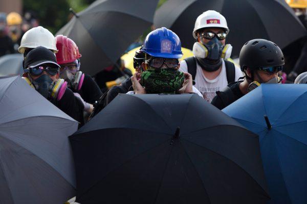 Protesters take cover behind umbrellas as police fire tear gas at them in Wong Tai Sin during a general strike in Hong Kong on August 5, 2019, as simultaneous rallies were held across seven districts. (Isaac Lawrence/AFP/Getty Images)