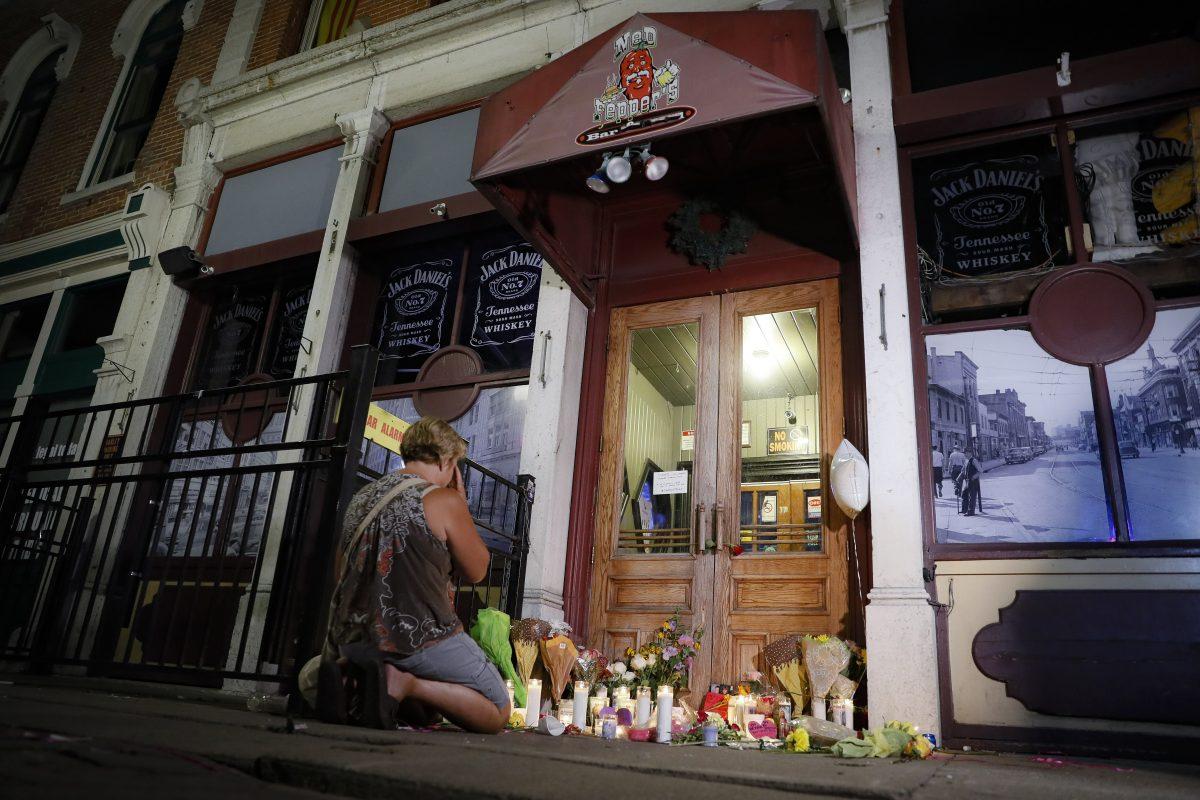 Mourners visit a makeshift memorial outside Ned Peppers bar following a vigil at the scene of a mass shooting, Sunday, Aug. 4, 2019, in Dayton, Ohio. (AP Photo/John Minchillo)