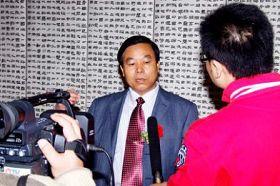 A TV station reporter interviewing Liu Xitong during the exhibition. (Minghui.org)