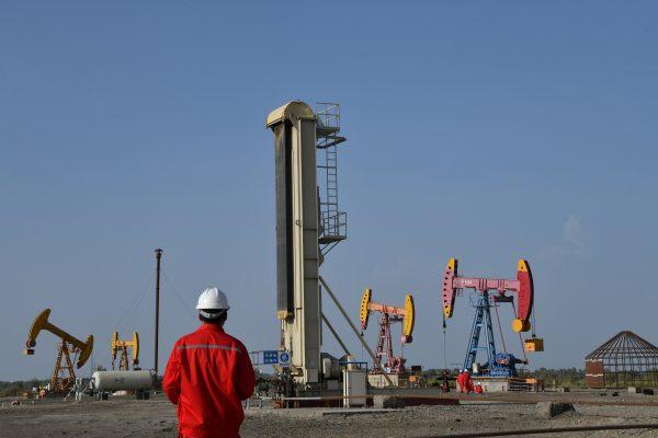Workers are seen near pumpjacks at a China National Petroleum Corp (CNPC) oil field in Bayingol, Xinjiang, China, on Aug. 7, 2019. (Reuters)