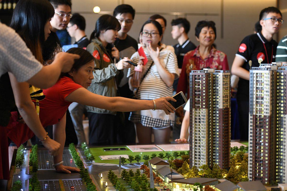 A woman points at the model of a residential compound by China Vanke as a sales agent introduces the property to the visitors at its showroom during the National Day "Golden Week" holiday, in Dongguan, Guangdong Province, China on Oct. 2, 2018. (Reuters)