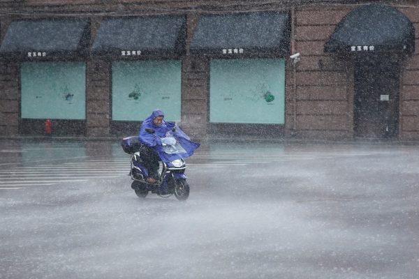 A man rides an electric scooter in the rainstorm as typhoon Lekima approaches in Shanghai, China on Aug. 10, 2019. (REUTERS/Aly Song)