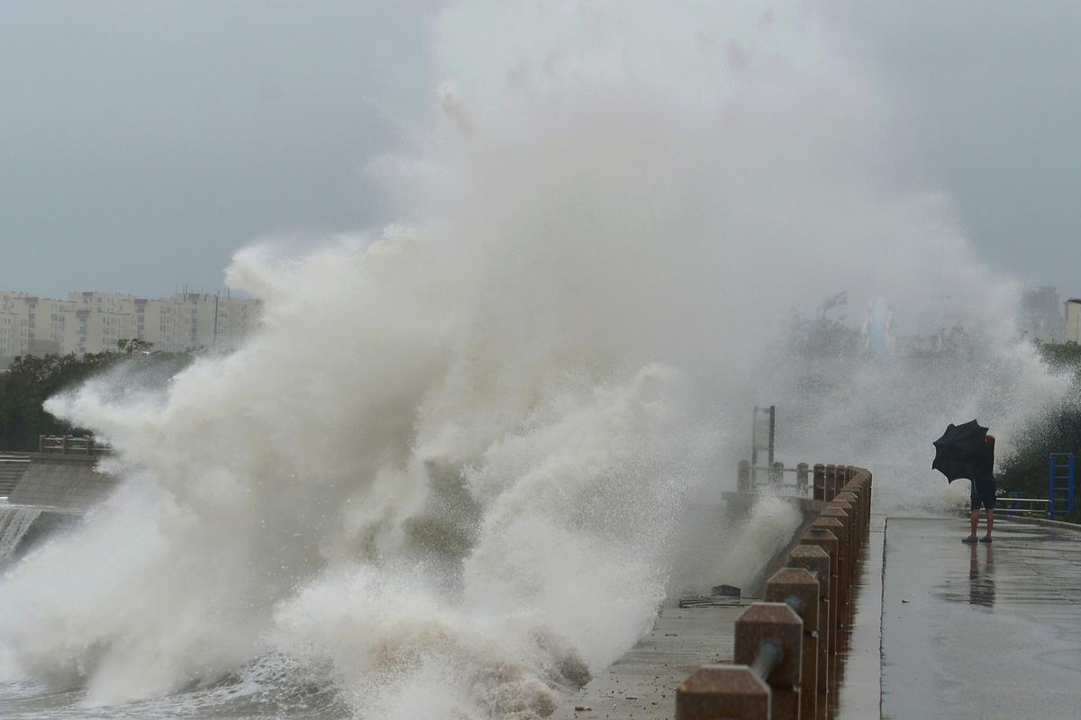 A wave brought by typhoon Lekima breaks on the shore next to a pedestrian in Qingdao, Shandong Province, China on Aug. 11, 2019. (Reuters)