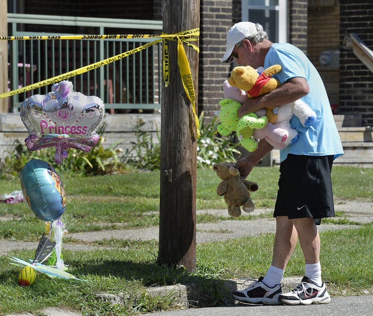 Paul Laughlin, 57, places stuffed animals outside a home at 1248 West 11th St. in Erie, Pa., where multiple people died in an early-morning fire, on Aug. 11, 2019. (Greg Wohlford/Erie Times-News via AP)