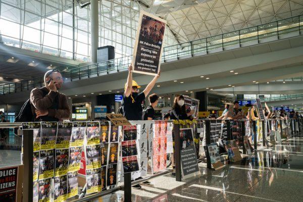 Protesters hold signs and handout leaflets to passing travelers at the Hong Kong International Airport in Hong Kong on Aug. 13, 2019. (Billy H.C. Kwok/Getty Images)