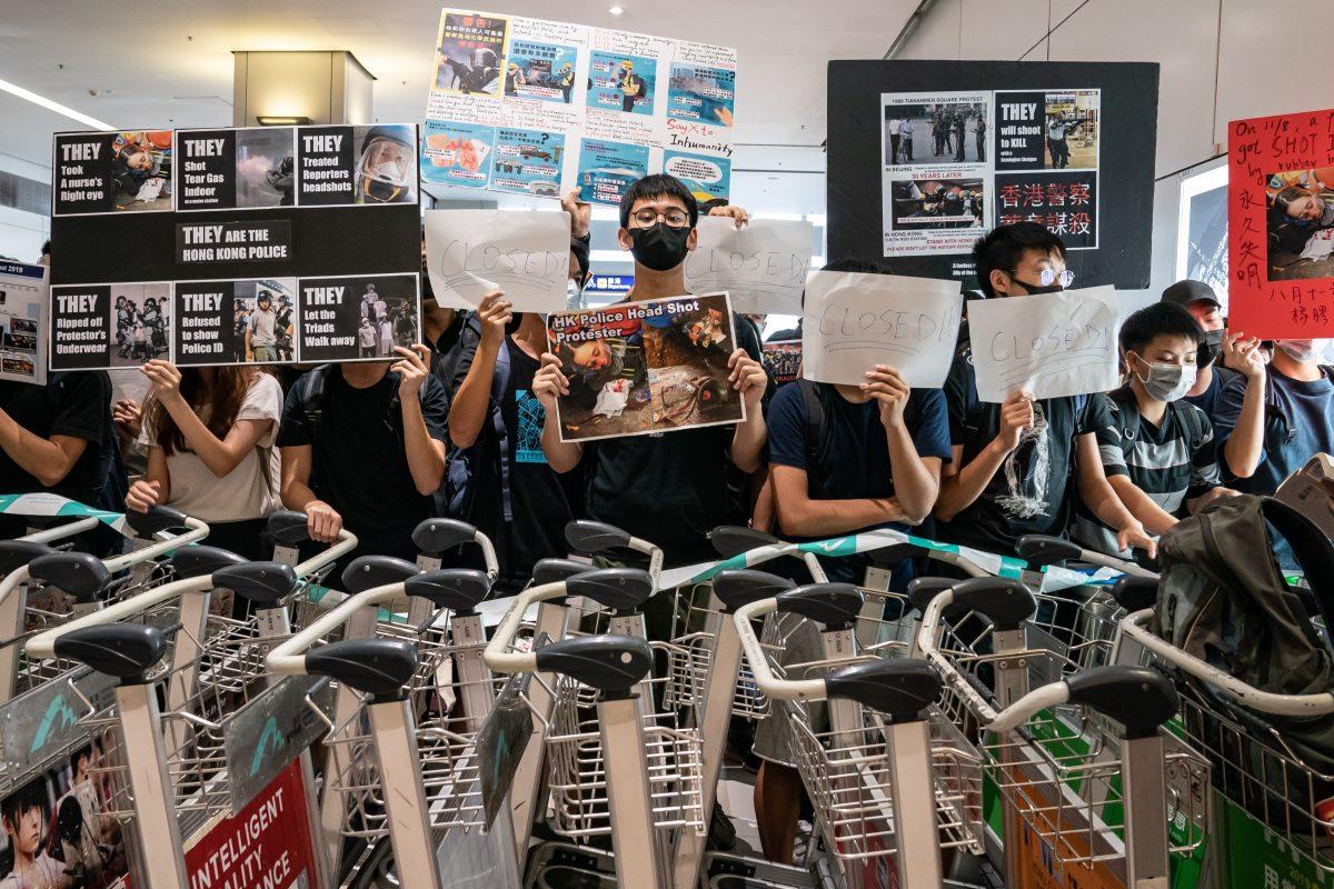 Protesters hold placards as they block the departure gate of the Hong Kong International Airport Terminal 2 during a demonstration in Hong Kong, on Aug. 13, 2019. (Anthony Kwan/Getty Images)