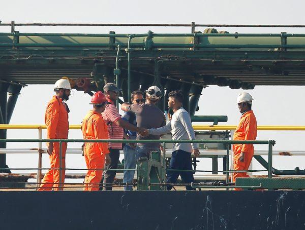 Two men are welcomed by crew members after embarking Iranian oil tanker Grace 1 as it sits anchored awaiting a court ruling on whether it can be freed after it was seized in July by British Royal Marines off the coast of the British Mediterranean territory, in the Strait of Gibraltar, southern Spain, on Aug.15, 2019. (Jon Nazca/Reuters)
