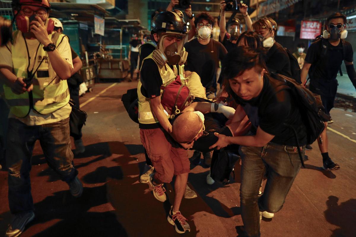 Medical staffs and protesters carry an injured man as they confront with policemen near the Shum Shui Po police station in Hong Kong on Aug. 14, 2019. (Vincent Yu/AP)