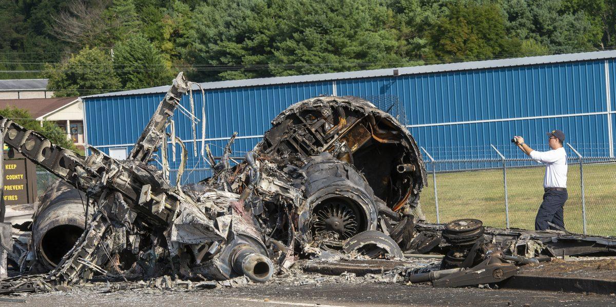 A member of the National Transportation Safety Board looks at the wreckage of a plane that Dale Earnhardt Jr., his wife and daughter, and two pilots and a dog were on when it crash-landed on Aug. 15, 2019, at the Elizabethton Municipal Airport in Elizabethton, Tenn., on Aug. 16, 2019. (David Crigger/Bristol Herald Courier via AP)