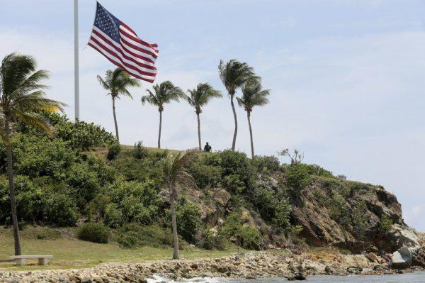 A man stands near a U.S. flag at half staff on Little St. James Island, in the U. S. Virgin Islands, a property owned by Jeffrey Epstein on Aug. 14, 2019. (Gabriel Lopez Albarran/AP Photo)