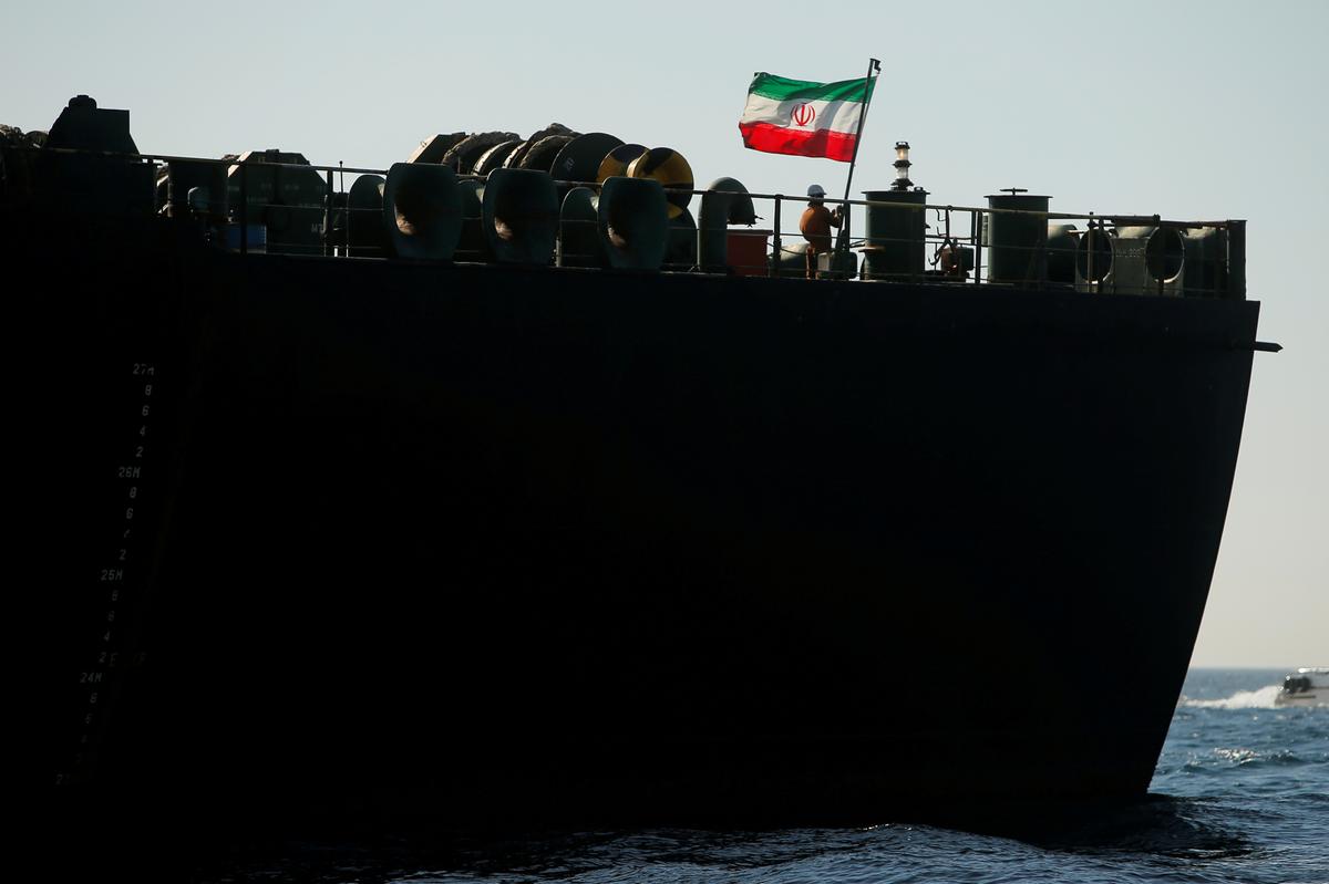 A crew member raises the Iranian flag on Iranian oil tanker Adrian Darya 1, previously named Grace 1, as it sits anchored after the Supreme Court of the British territory lifted its detention order, in the Strait of Gibraltar, Spain, on Aug. 18, 2019. (Reuters/Jon Nazca)