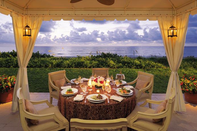 Table set for six under canopy looking out at the ocean at dusk at the Four Seasons Resort Palm Beach. (Courtesy of Discover the Palm Beaches)