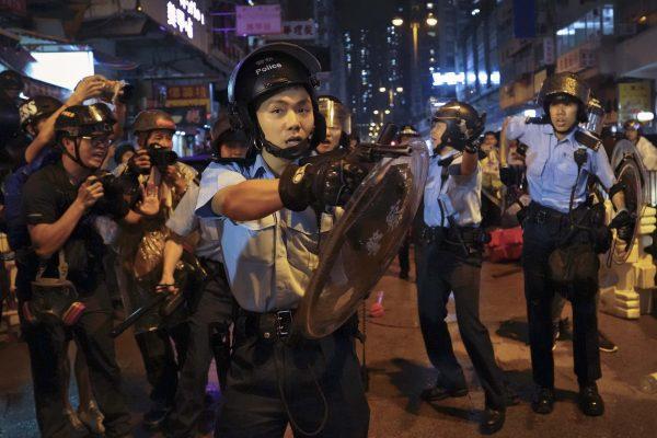 A policeman points his gun after confronting demonstrators during a protest in Hong Kong, on Aug. 25, 2019. (AP Photo/Vincent Yu)