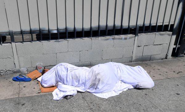 A homeless person sleeping under sheets along a sidewalk in Los Angeles on Aug. 22, 2019. (Frederic J. Brown/AFP/Getty Images)
