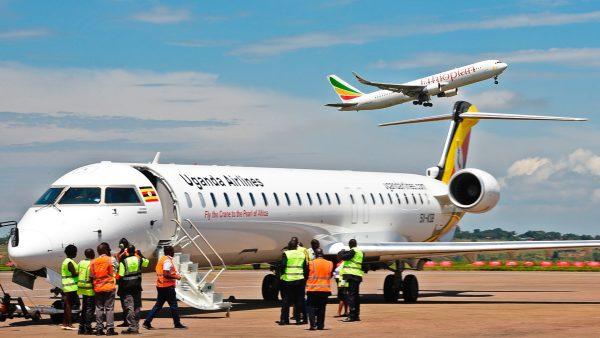 Ground crew prepare a Uganda Airlines Bombadier aircraft for departure as an aircraft operated by Ethiopian airlines takes off in the background at Entebbe airport during the launch of Uganda Airlines maiden flight to Jomo Kenyatta International Airport in Nairobi on Aug. 27, 2019. (ISAAC KASAMANI/AFP/Getty Images)